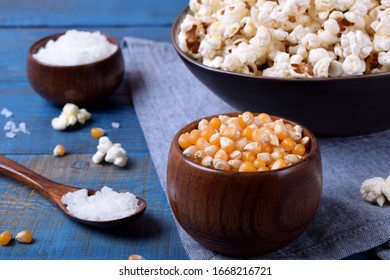 Unpopped corn kernels for making popcorn in a wooden cup on blue table