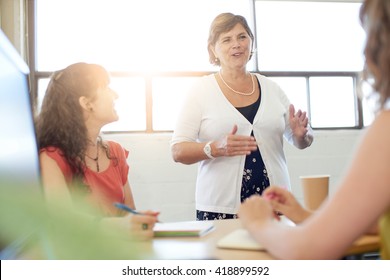 Unposed Group Of Creative Business People In An Open Concept Office Brainstorming Their Next Project.