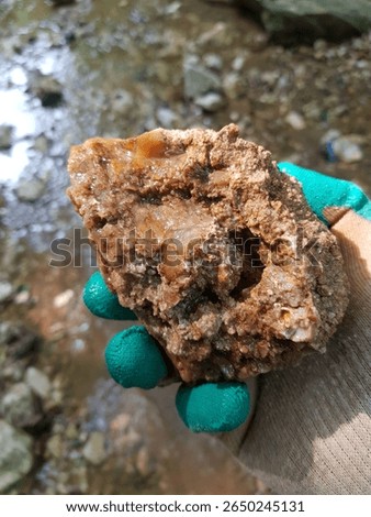 Unprocessed sample of chalcedony in hand found in a ravine, field photo