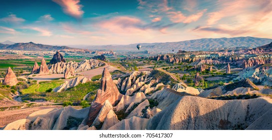 Unreal world of Cappadocia. Colorful sunrise in Red Rose valley in April. Cavusin village located, Nevsehir Province in the Cappadocia region of Turkey, Asia. Traveling concept background