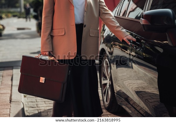 Unrecognisable Elegant Business Woman with Briefcase\
Opening Door of Luxury\
Car