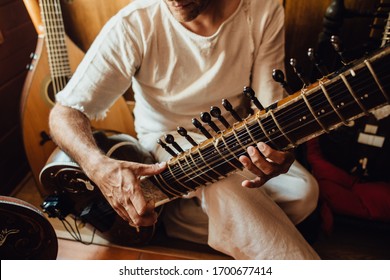 Unrecognisable Indian musician playing a sitar, traditional indian musical instrument