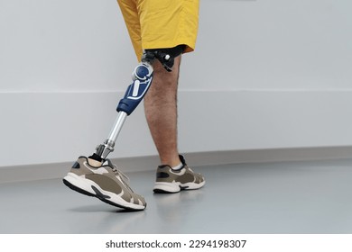 Unrecognisable male in yellow coloured shorts wearing prosthetic leg walking in luminous spacious corridor - Powered by Shutterstock