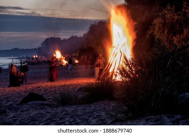 Unrecognisable people celebrating summer solstice with bonfires on beach