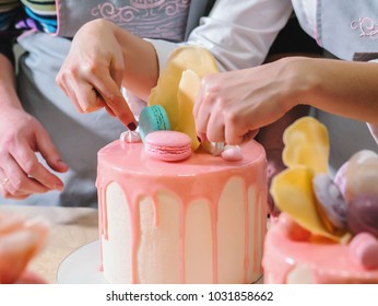 Unrecognisable woman decorating mousse glaze cake with rose, macarons, hands detail, focus on the cake. DIY, sequence, step by step, part of series. - Powered by Shutterstock