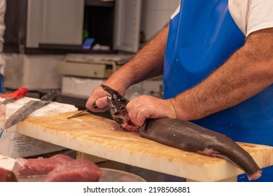 Unrecognizable Adult Man Fishmonger Cutting Fresh Fish At Market Place As Daily Life Concept