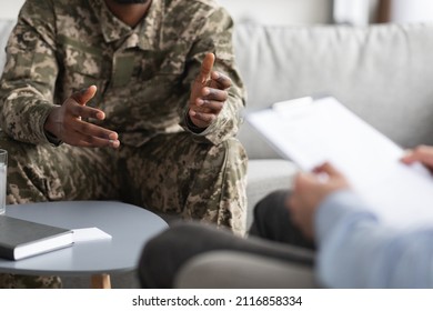Unrecognizable african american man in uniform soldier talking to psychologist, sitting on couch at clinic and gesturing, doctor holding medical chart, cropped shot. PTSD in military veterans - Powered by Shutterstock