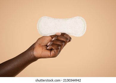 Unrecognizable African American Woman Hand Holding Daily Pad, Posing Over Beige Studio Background, Isolated, Cropped, Copy Space. Female Period And Intimate Hygiene, Menstrual Products Concept