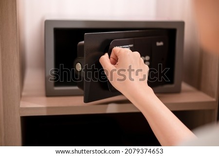 Unrecognizable Asian businesswoman opening a safe box or vault storage. Safety storage in luxury hotel for guests or customers keep their valued items secure.
