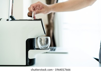 Unrecognizable Asian Man Brewing An Espresso Coffee By Using An Automatic Coffee Maker Machine On The Table Close Up. A Modern Coffee Capsule Machine.