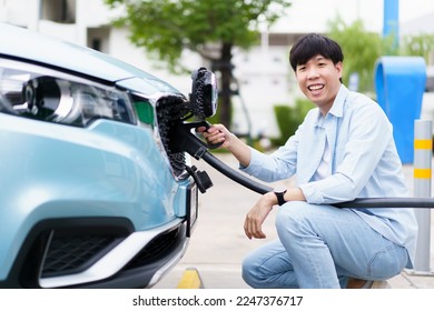 Unrecognizable Asian man holding AC type 2 EV charging connector at EV charging station, man preparing an EV - electric vehicle charging connector for recharge a vehicle. - Shutterstock ID 2247376717