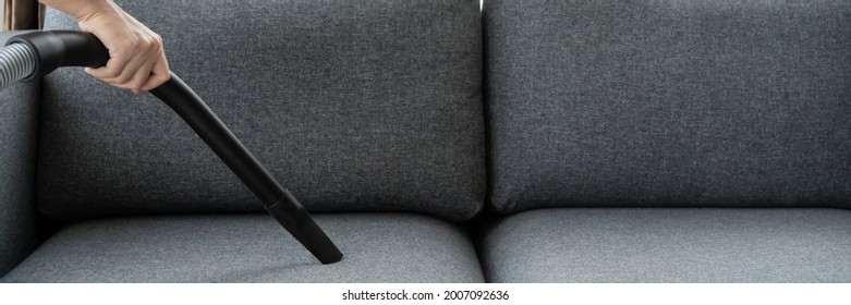 Unrecognizable Asian Man Housekeeper Using A Vacuum Machine Vacuuming A Dust On A Sofa In Living Room Close Up. A Man Cleaning And Sanitizing His House For Hygiene Living. Vacuum Machine And Housework