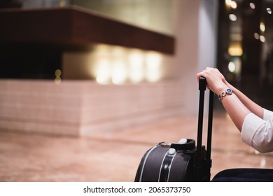 Unrecognizable Asian young woman sitting and holding her hard suitcase in the hotel lobby. Business travel concept. - Powered by Shutterstock