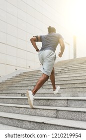 Unrecognizable athletic man in sportswear running up concrete stairs outdoors while having daily morning workout, rear view - Shutterstock ID 1210219954