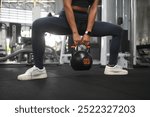 Unrecognizable athletic woman training with kettlebell in the gym