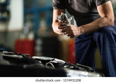 Unrecognizable auto mechanic using a rag while cleaning his hands in a garage. - Powered by Shutterstock