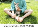 unrecognizable barefoot child playing with a cute kitten on the lawn. favorite pet. A moment of joy and happiness. Happy childhood. Love for cats. cat day