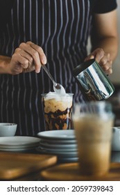 Unrecognizable  Barista Using Spoon To Gentle Topping Glass Of Sweet Coffee At Bar Counter With White Milk Froth From Metal Jar To Enhance Taste Of Softness And Mellowness