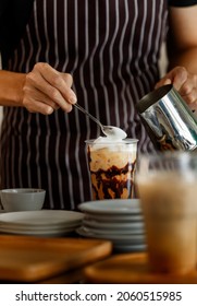 Unrecognizable  Barista Using Spoon To Gentle Topping Glass Of Sweet Coffee At Bar Counter With White Milk Froth From Metal Jar To Enhance Taste Of Softness And Mellowness