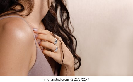 Unrecognizable Beautiful Brunette Young Woman Wearing Bra, Gently Touching Her Chest On A Beige Copy Space Background. Self Love, Body Image, Insecurity, Sensuality, Female Pleasure Concept. 