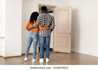 Unrecognizable Black Couple Hugging Standing Back To Camera Near Opened Door In New House Indoors. Real Estate Buyers, Apartment Ownership, Purchase And Rent Concept. Rear View