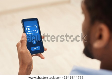 Unrecognizable black guy using mobile phone, buying goods and services, over shoulder shot, closeup, copy space, creative image for modern mobile application and payment systems