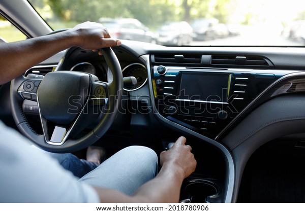 Unrecognizable black man driver sitting in brand\
new auto, over shoulder shot, copy space. Cropped of african\
american guy holding hands on car gear and steering wheel, making\
test drive before\
buying