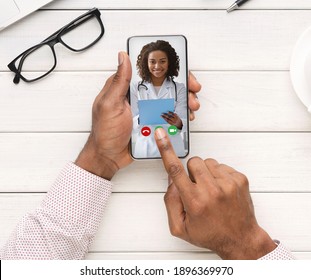 Unrecognizable Black Man Making Video Call To His Female Doctor While Working In Office, Having Web Conference With Smiling African Therapist Lady, Enjoying Telemedicine, Creative Collage, Top View - Powered by Shutterstock