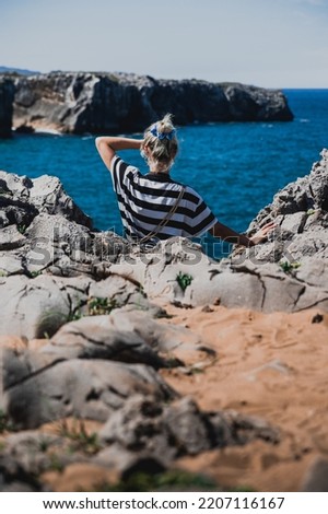 
unrecognizable blonde girl with striped shirt looking to the ocean