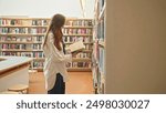 Unrecognizable brunette browsing a book in a library or bookstore, exam preparation, teacher training, higher education, e-learning for students, research project work for masters, bachelors, interns