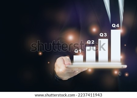 Unrecognizable businessman holding a tablet with a beautiful illuminated hologram showing a quarterly report in bar chart close up with copyspace. Quarter growth concept.