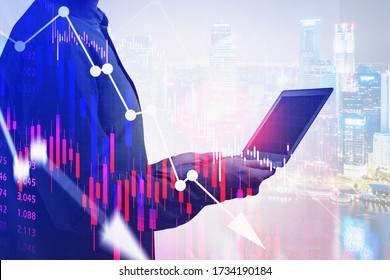 Unrecognizable businessman using laptop in blurry night city with double exposure of falling financial chart. Concept of crisis and trading. Toned image