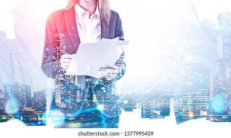 Unrecognizable businesswoman with documents standing over night city background with double exposure of network interface. Concept of hi tech. Toned image - Powered by Shutterstock