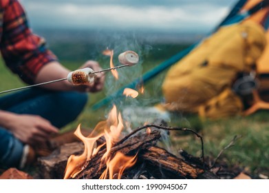 Unrecognizable Campers Holding Marshmallows On A Stick Above The Camp Fire In A Nature