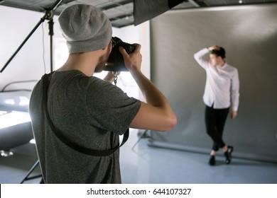 Unrecognizable Casual Photographer Taking Shots Of Male Model In Studio. Fashion Photoshoot Backstage