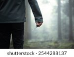 Unrecognizable Caucasian male holding a hunting knife in a foggy forest scene. Danger of traveling alone concept, scary, menacing atmosphere.