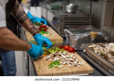 Unrecognizable Chef With Gloves Cutting Vegetables Indoors In Restaurant Kitchen.