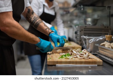 Unrecognizable Chef With Gloves Cutting Vegetables Indoors In Restaurant Kitchen.