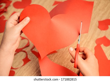 Unrecognizable Child Cuts A Red Paper Heart