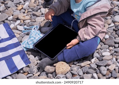 An unrecognizable child points at the black screen of the tablet. The boy points to a tablet, plays games, a mobile application for children, which has a place to copy. High quality photo - Powered by Shutterstock