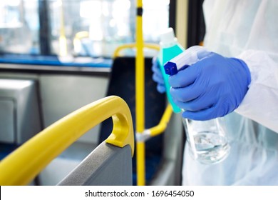 Unrecognizable cleaning person applying sanitizer or disinfectant on bus vehicle handlebars for public health. Stop spreading of virus.