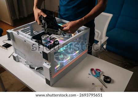 Unrecognizable computer technician installing new graphics card into modern custom-built pc with RGB lighting, enhancing gaming performance and visual experience, upgrading desktop PC.