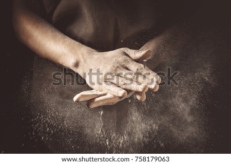 Unrecognizable cook clapping hands with flour while making dough.