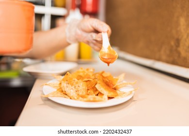 Unrecognizable Cook Pouring Hot Sauce Over Ready-to-serve Nachos In A Restaurant Kitchen