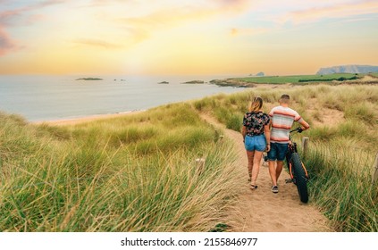 Unrecognizable couple with a fat bike taking a walk through the dunes of the beach - Powered by Shutterstock