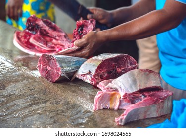 Unrecognizable Creole Man Cutting Big Tuna Fish For Sale At The Street Market.