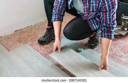 Unrecognizable crouched female bricklayer placing tiles to install a floor