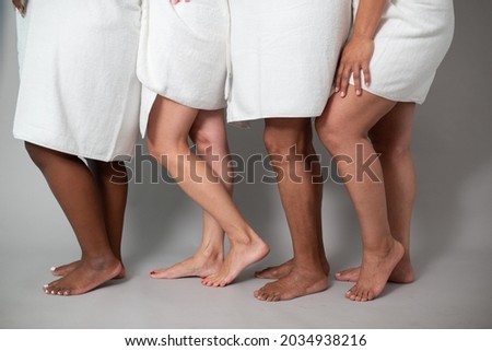 Unrecognizable diverse barefooted women in bath towels