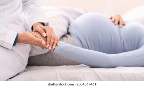 Unrecognizable Doctor Holding Pregnant Woman's Hand Supporting Patient Lying In Bed Indoor. Selective Focus - Powered by Shutterstock