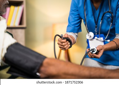 Unrecognizable Doctor Or Nurse Checking Blood Pressure Or BP Of Patient At Home